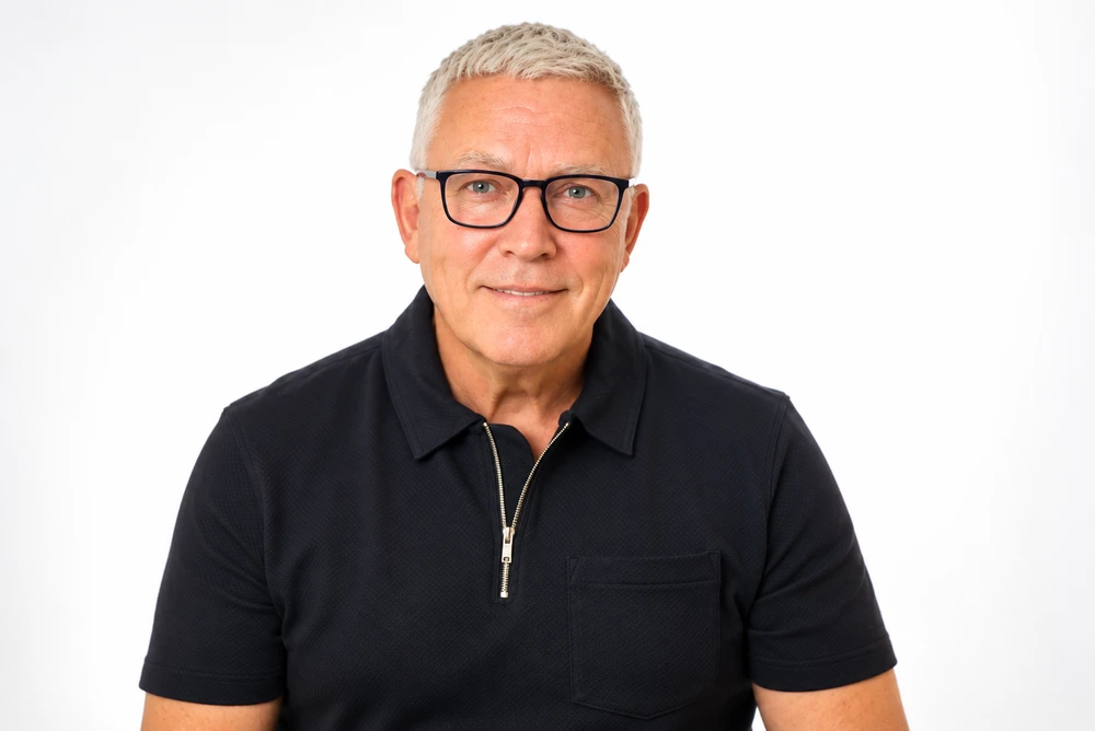 Kerry Ball, in glasses and a black polo shirt, looking directly at the camera.